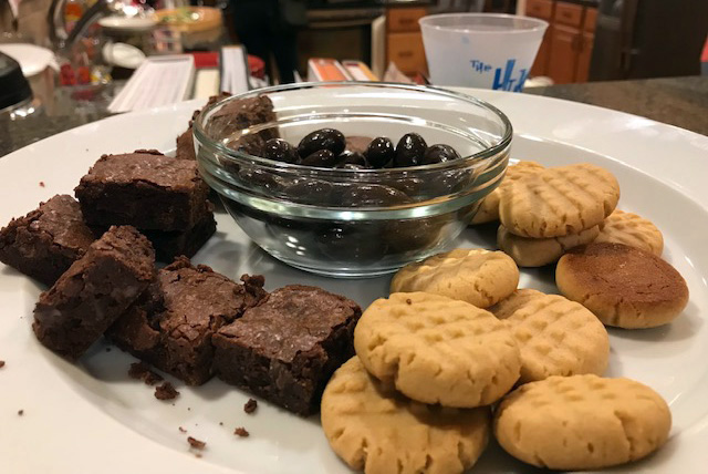 Brownies, chocolate-covered almonds, and peanut butter cookies on a plate.