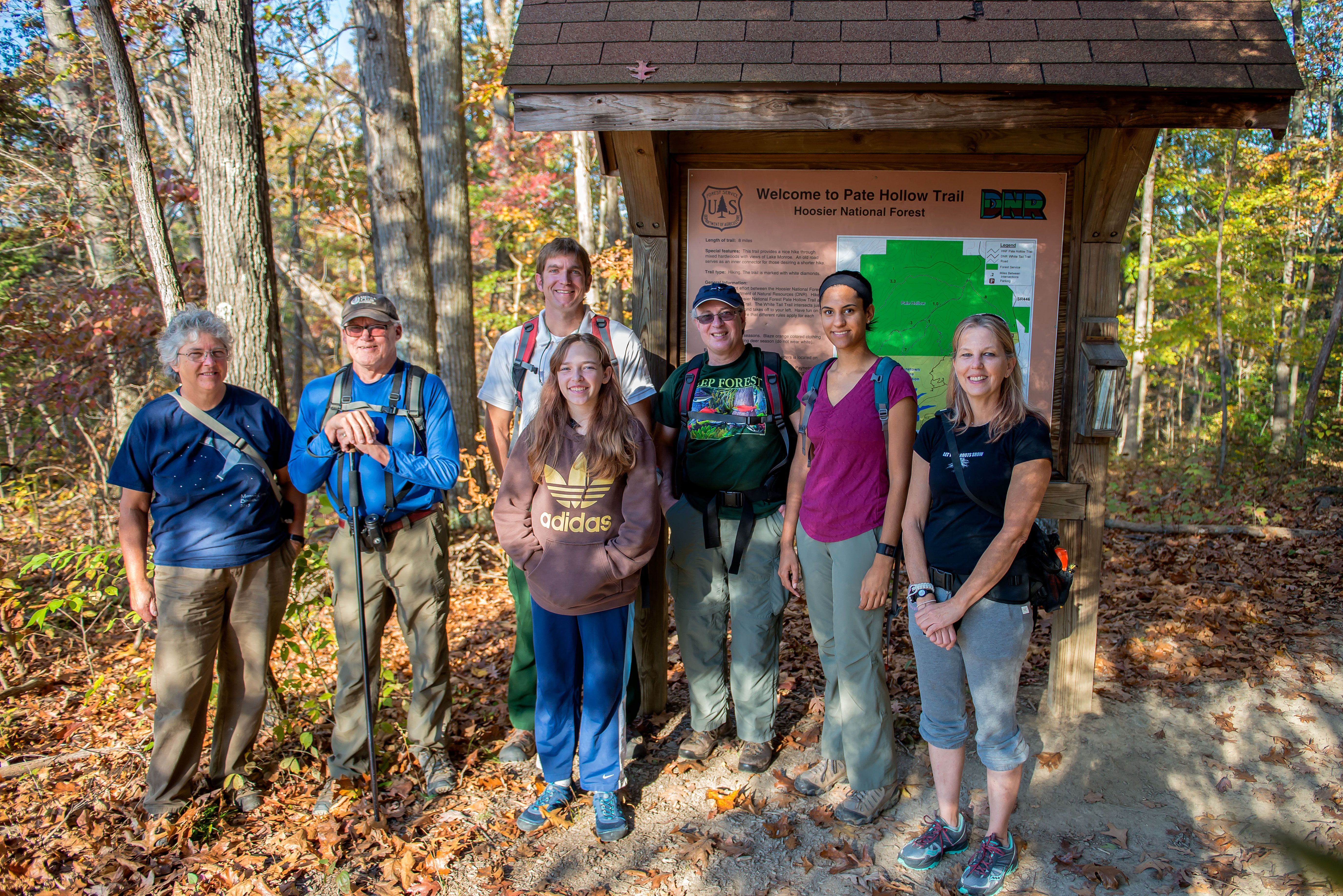 A group of seven people gather in front of the Pate Hollow trailhead sign in the Hoosier National Forest.