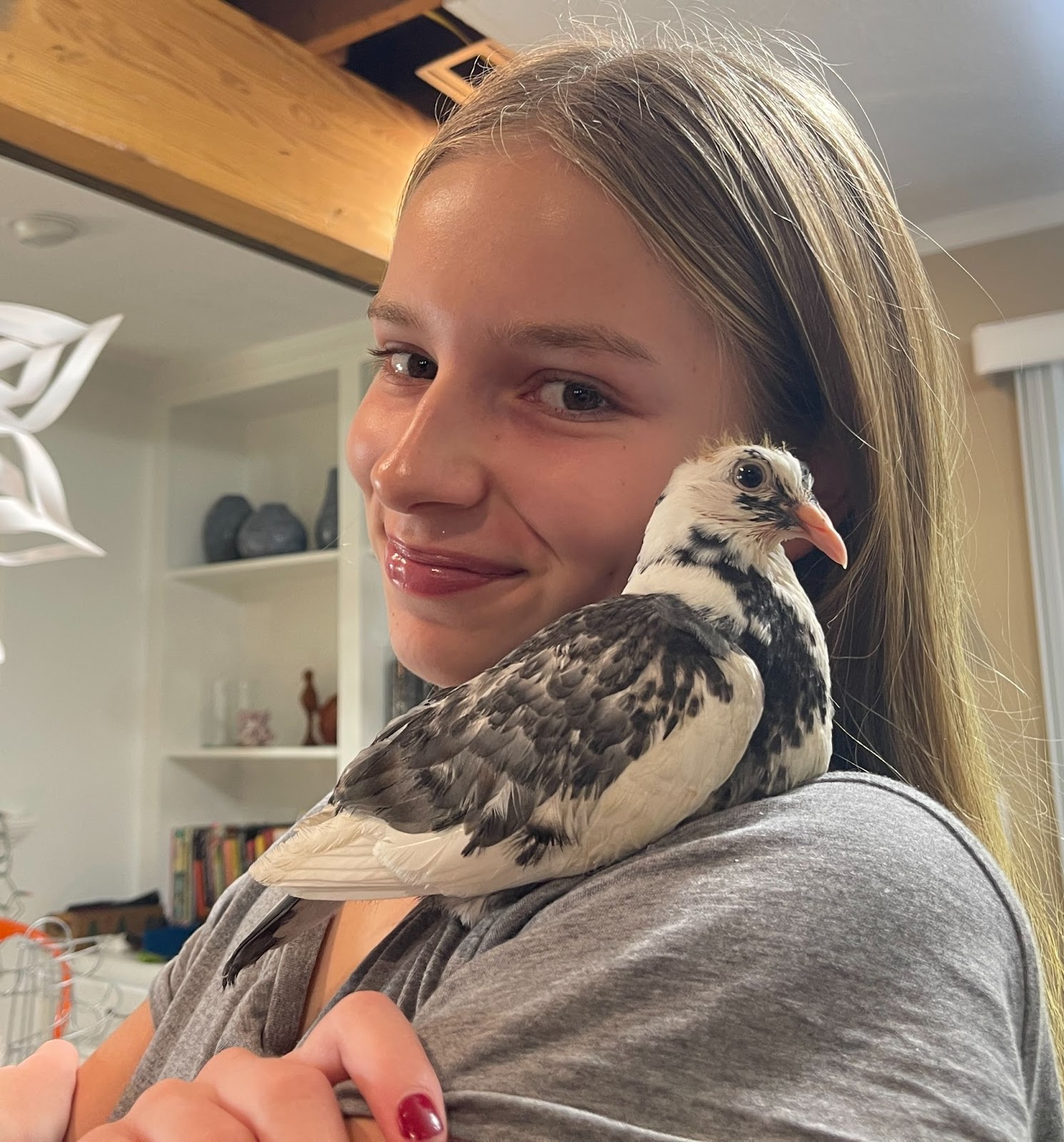 Lily Rieman, a teenage girl, with her pet pigeon with white and speckled black plumage