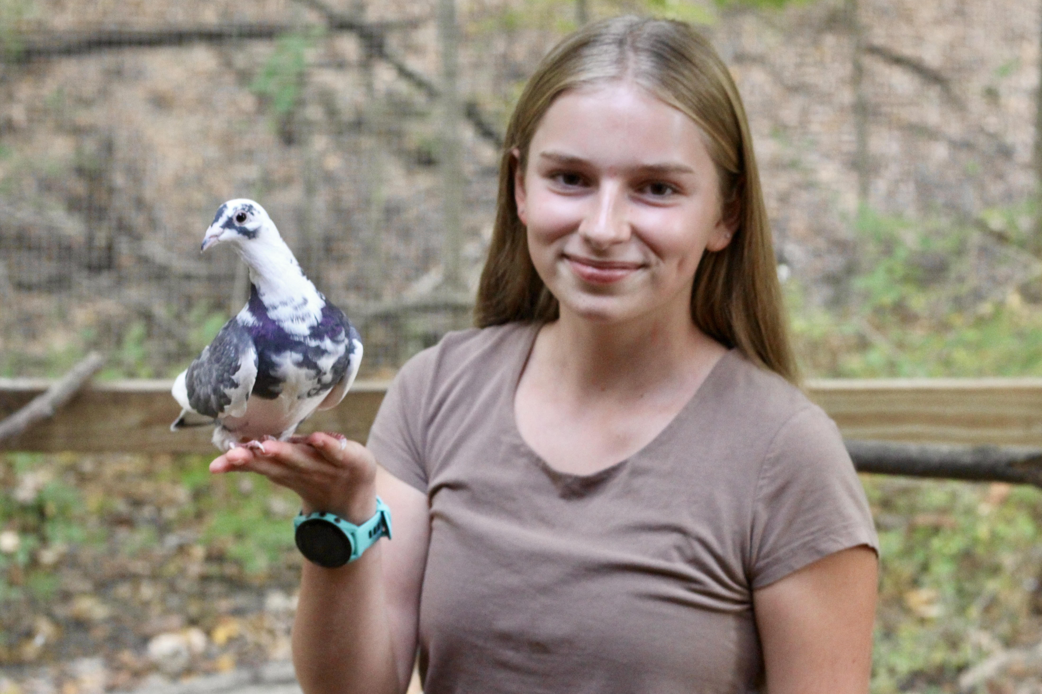Lily Rieman, a teenage girl with long blonde hair, holding a white and black pigeon