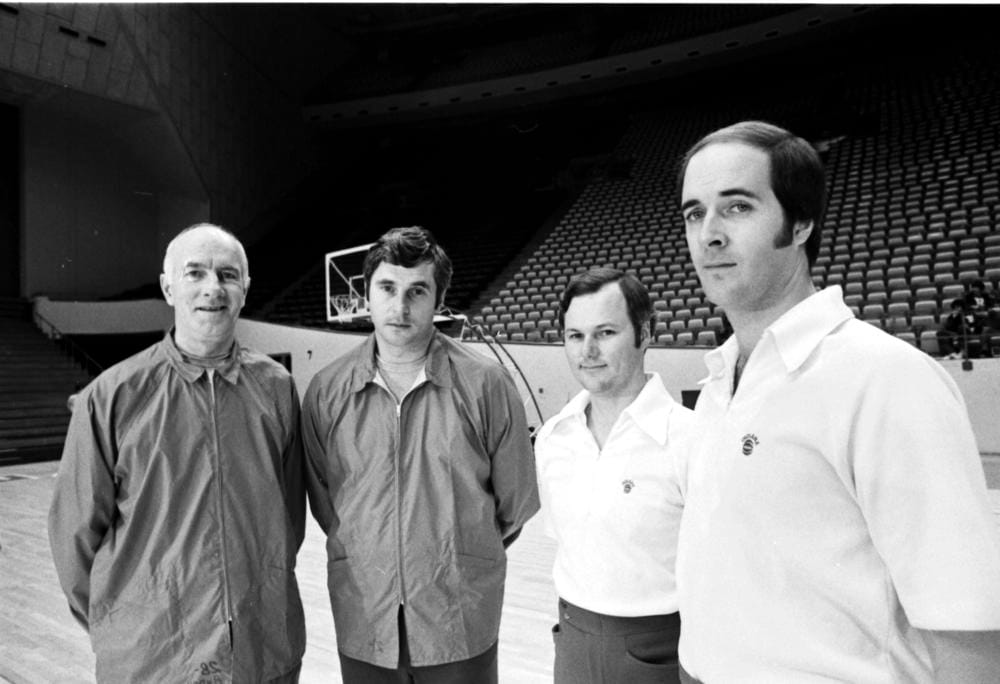 Four men, IU basketball coaches Harold Andreas, Bobby Knight, Bob Donewald, and Bob Weltlich, pose for a photo on the basketball court inside IU's Assembly Hall