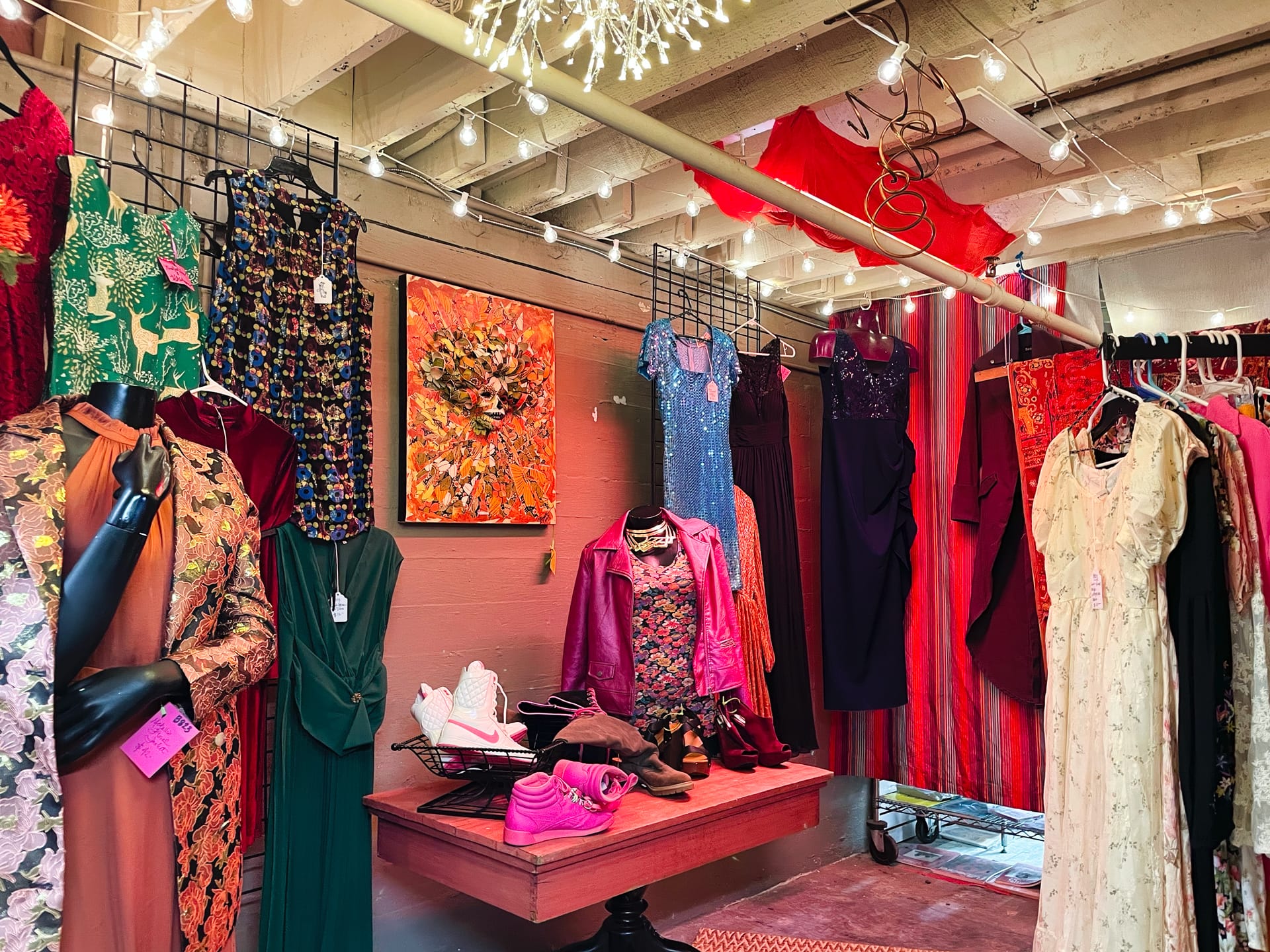 a clothing booth at an antique mall. The racks are hung with bright red, pink, and orange garments, among others.