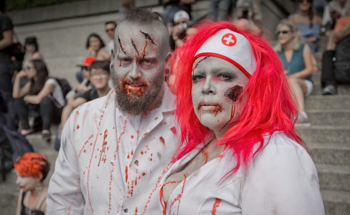 A man and a woman dressed as zombies in doctor and nurse outfits.