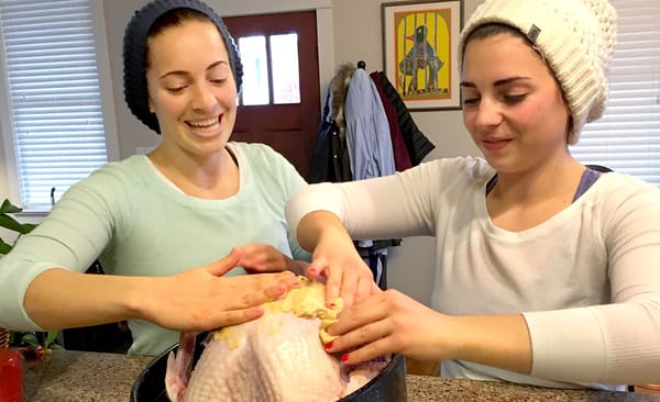 Ruthie Cohen's daughters, (l-r) Arianna and Eve, lather the uncooked turkey with mustard in preparation for Thanksgiving dinn