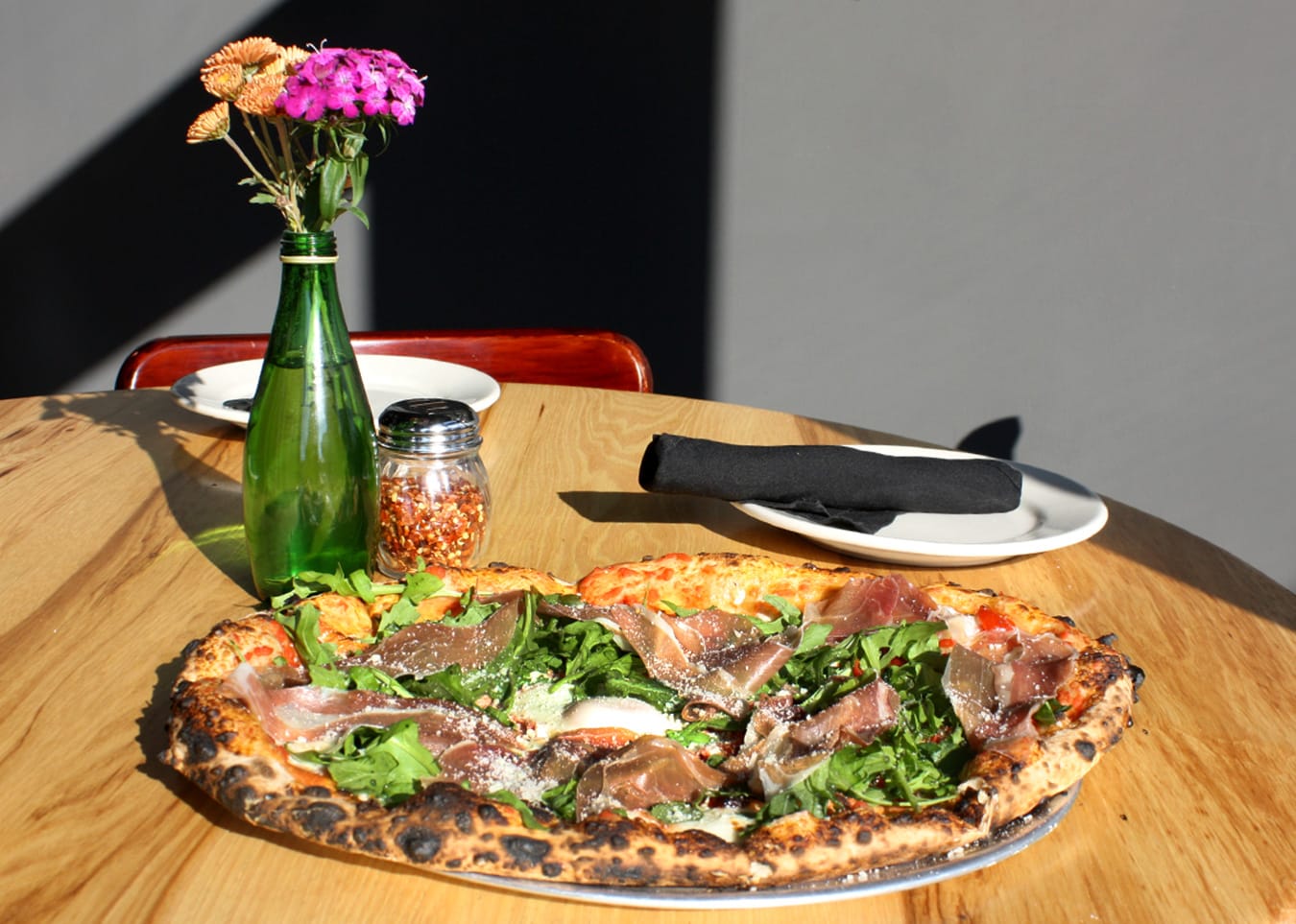 A prosciutto arugula pizza from King Dough sitting with flowers from Harvest Moon Flower Farm. | Photo by Jonna Mary Yost