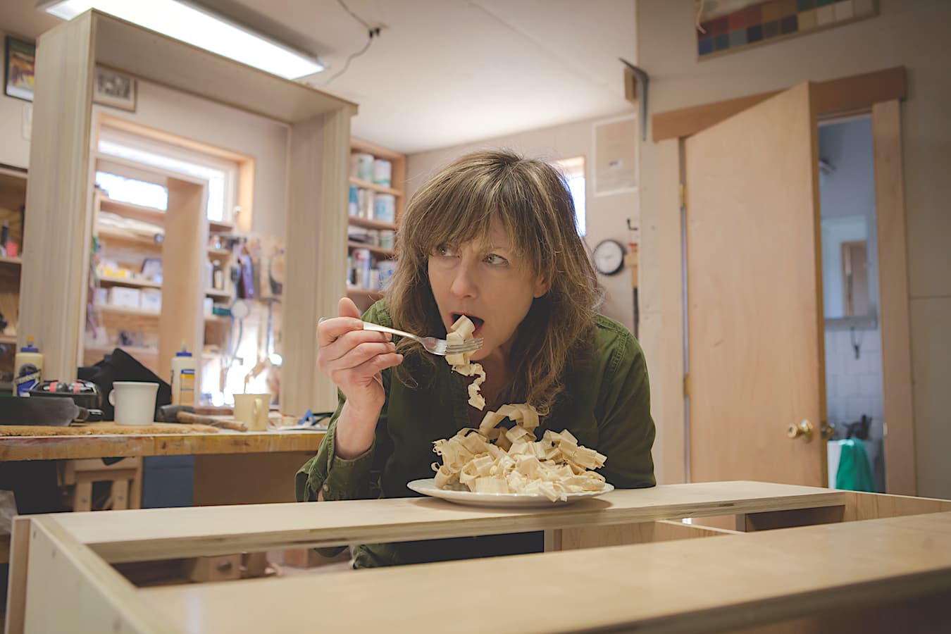 Nancy Hiller eating wood shavings in her workshop. An accomplished woodworker, Hiller is also the author of the books ‘Shop Tails: The Animals Who Help Us Make Things Work,’ ‘Making Things Work: Tales from a Cabinetmaker’s Life,’ and ‘The Hoosier Cabinet in Kitchen History,’ among others, as well as articles in several trade publications. | Courtesy photo