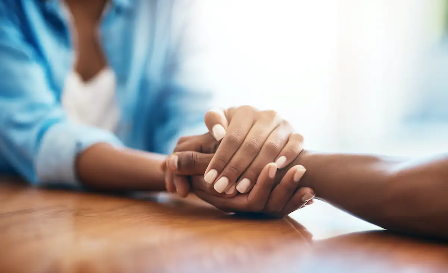 In addition to being exposed to a different way of life, you might also find unexpected points of connection just by asking a relative about their early life. | Photo by <a href="https://www.gettyimages.com/detail/photo/you-have-my-full-support-royalty-free-image/1135286661?phrase=holding hands at table black&adppopup=true" target="_blank" rel="noopener">PeopleImages/iStock via Getty Images</a>