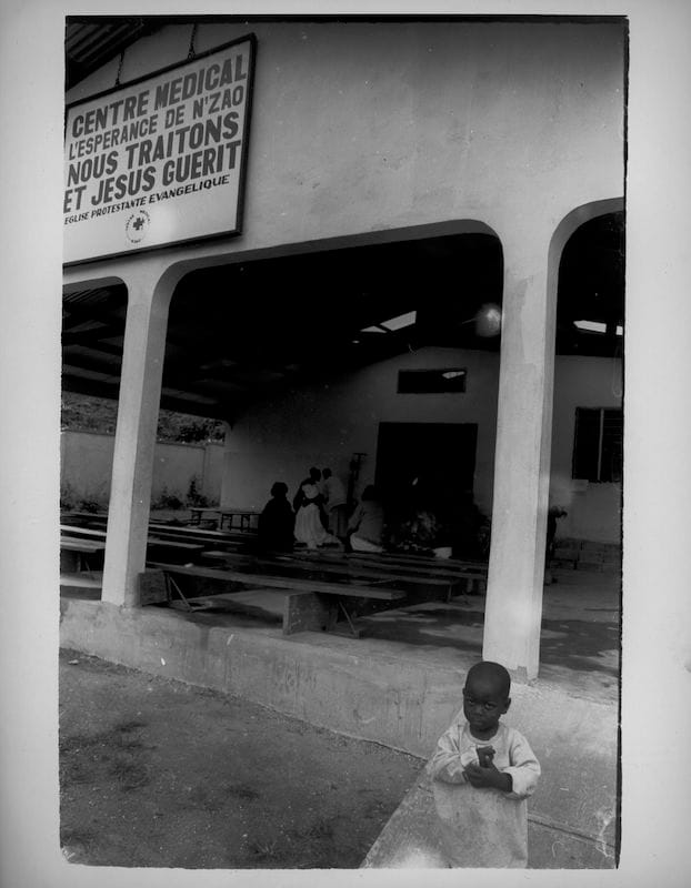 Les Fantômes de N’Zao (The Ghosts of N’Zao), N’Zao, Guinea, 2009, Gelatin Silver Print. Young boy stands outside of Hope Medical Clinic.