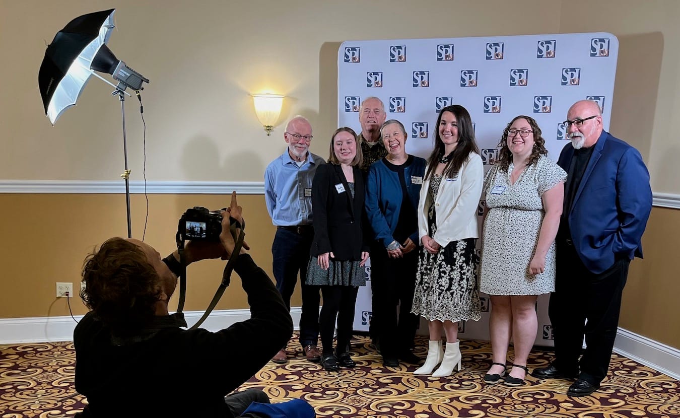 Limestone Post writers get their photos taken by Benedict Jones, a news anchor at WFHB Community Radio and an LP contributor, at the 2023 “Best in Indiana” Journalism Contest hosted by the Indiana Pro Chapter of the Society of Professional Journalists. Those being photographed are (l-r) Steve Hinnefeld, Haley Miller, Steven Higgs, Rebecca Hill, Christine Brackenhoff, Christina Avery, and Michael G. Glab. | Limestone Post